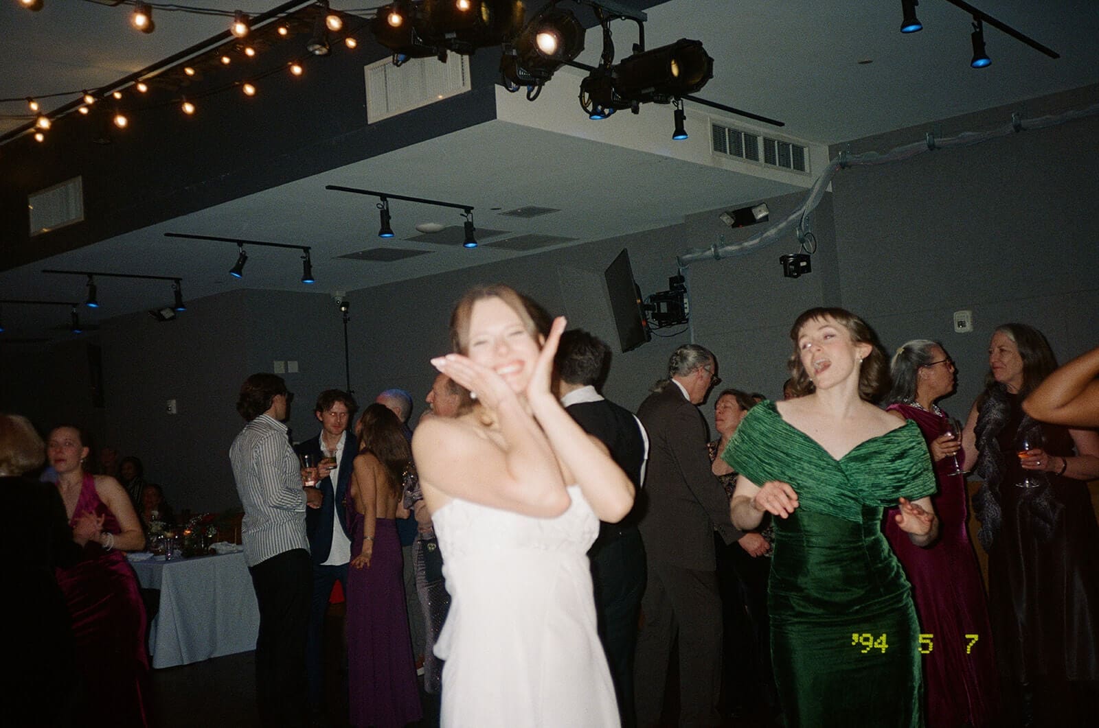 Candid wedding photos of the bride dancing with guests beneath string lights at City Winery Boston.