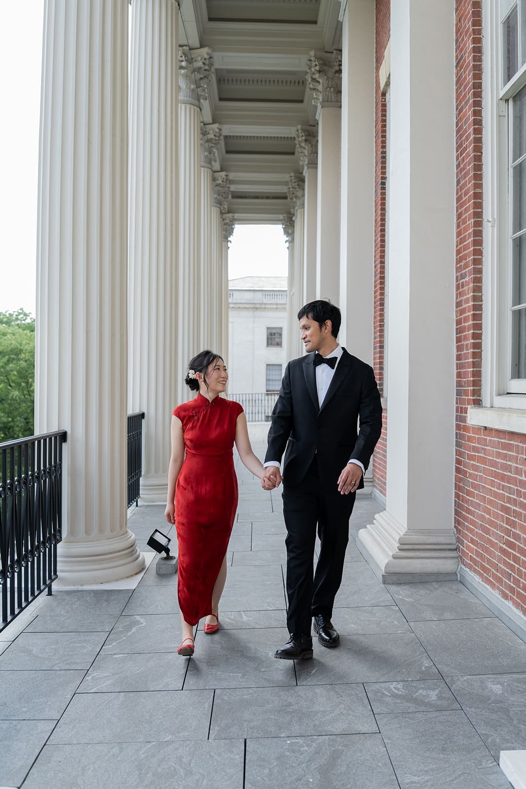 Newlyweds walk together along a columned balcony near Boston City Hall.