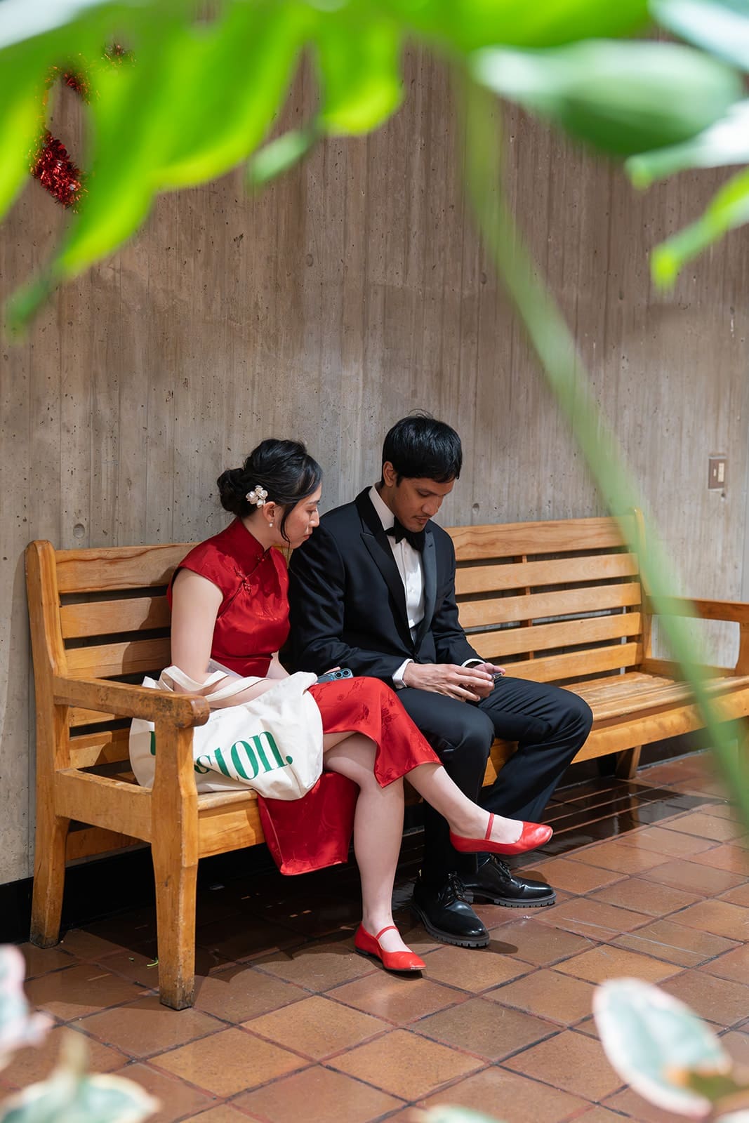 Newlyweds sit together on a wooden bench inside Boston City Hall.