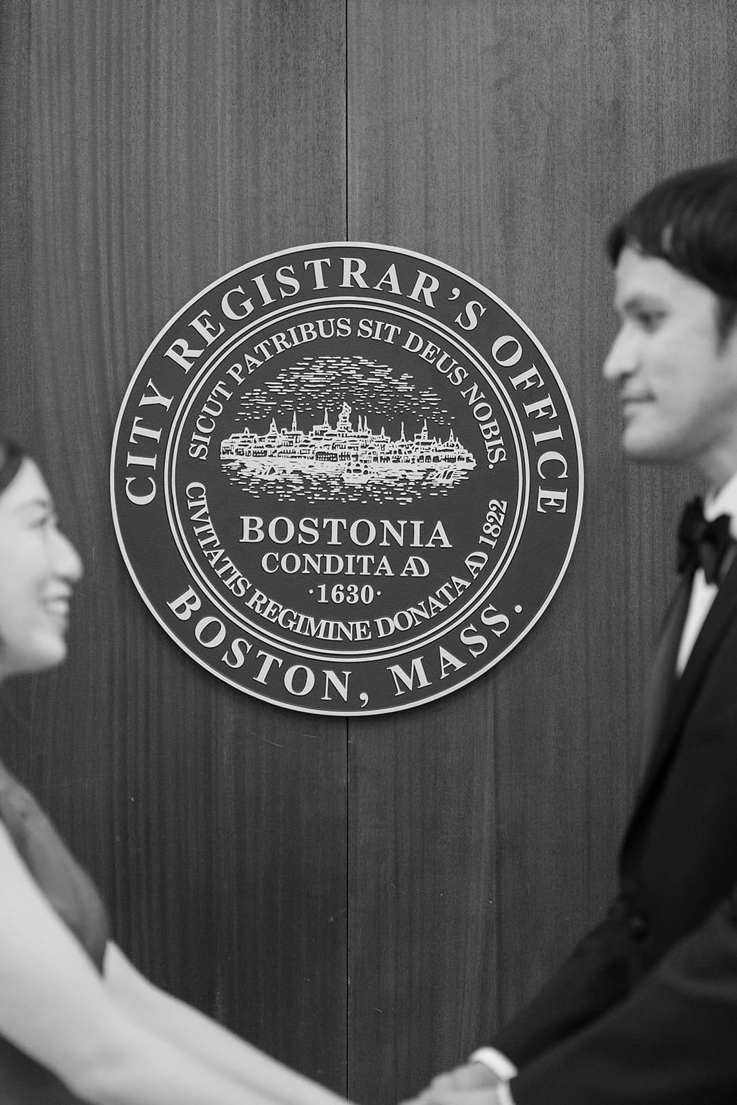 Black-and-white photo of a couple beside the Boston Registry Division seal.
