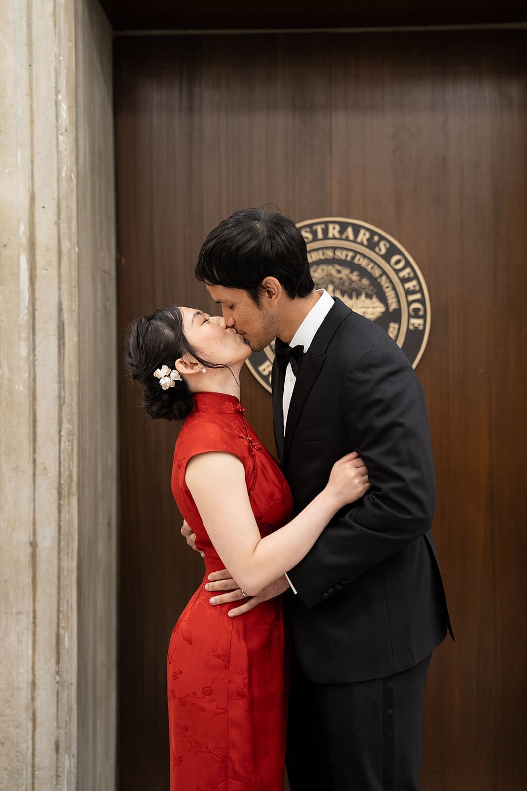 Newlyweds kiss in front of the Registry Division doors during their Boston City Hall wedding.