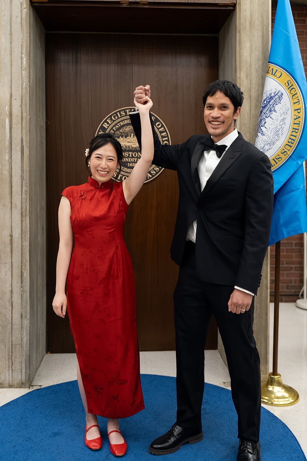 Couple raises their joined hands in celebration after their Boston City Hall ceremony.