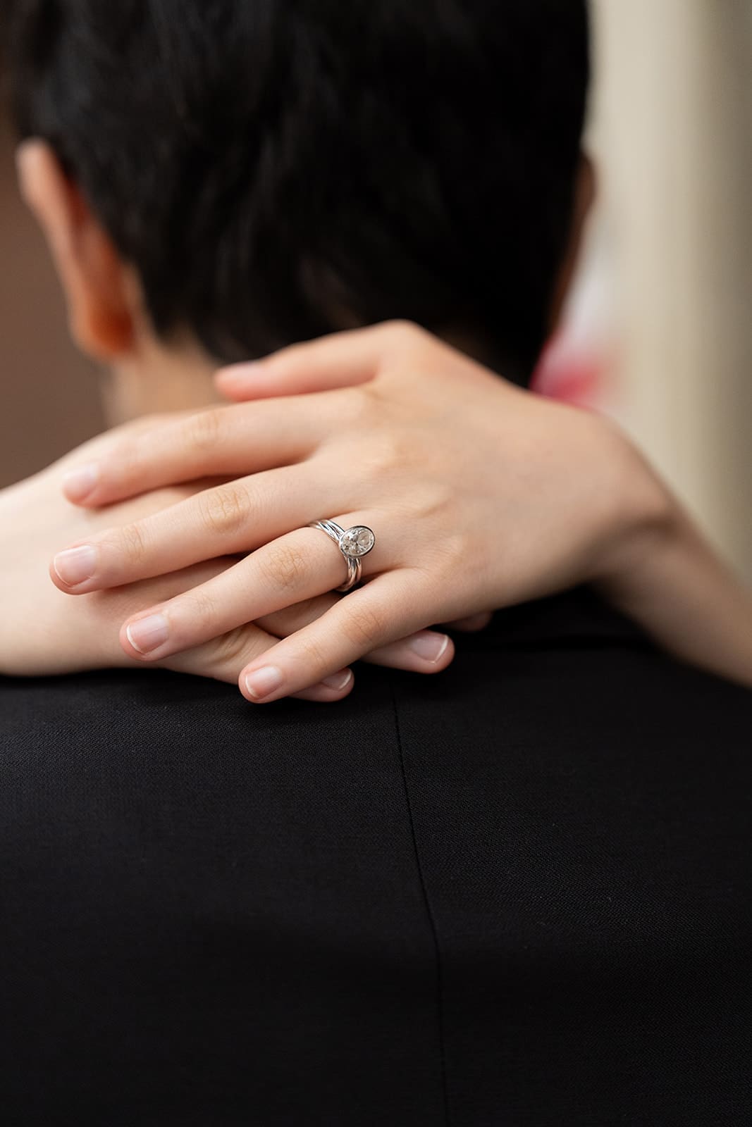 Close-up of a bride’s wedding ring as she embraces her partner.