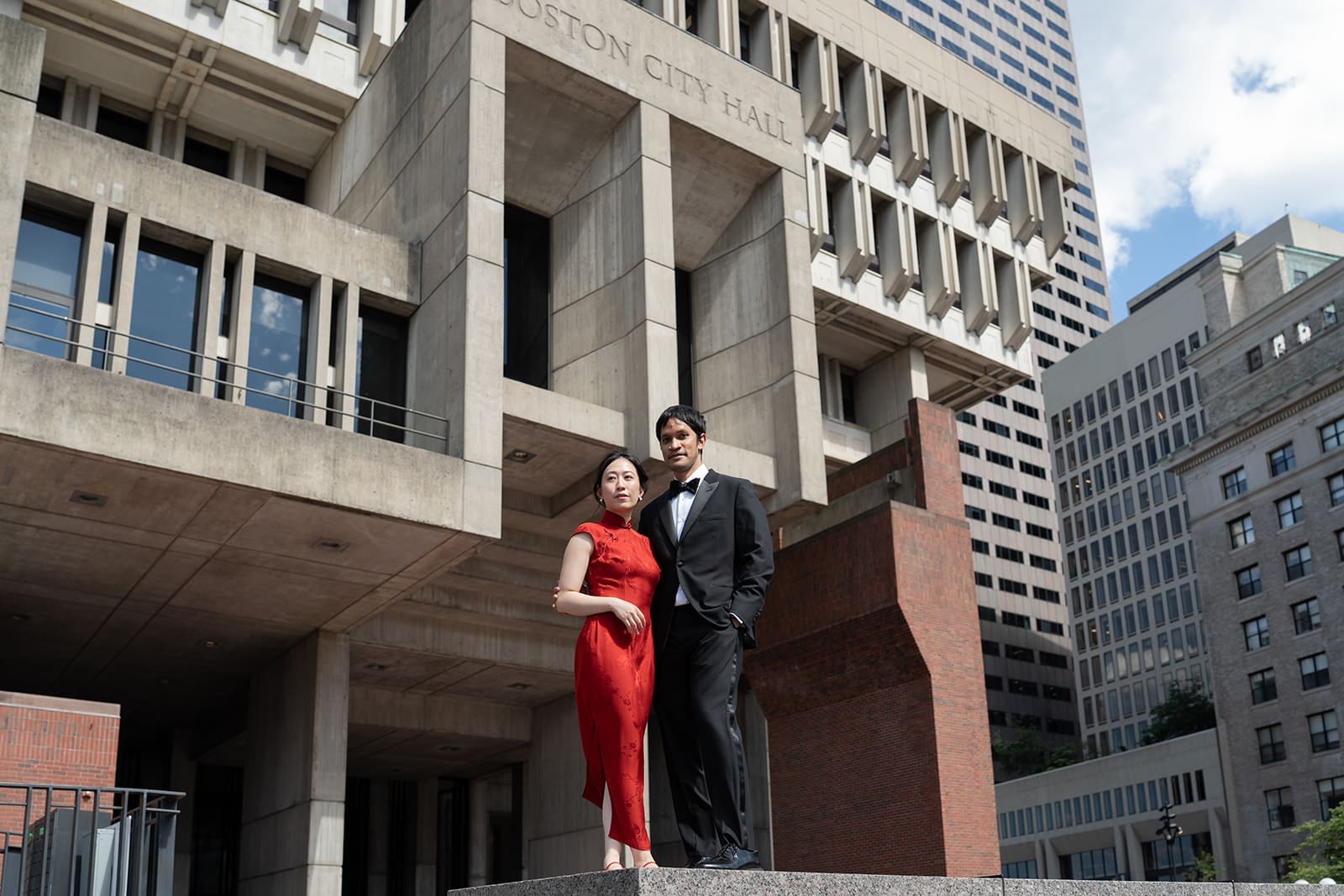 Newlyweds pose beneath the concrete architecture outside Boston City Hall.
