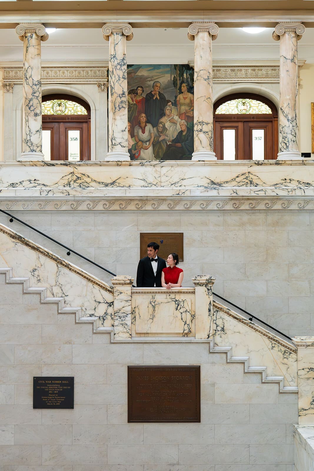 Couple stands on an ornate marble staircase inside Boston City Hall.