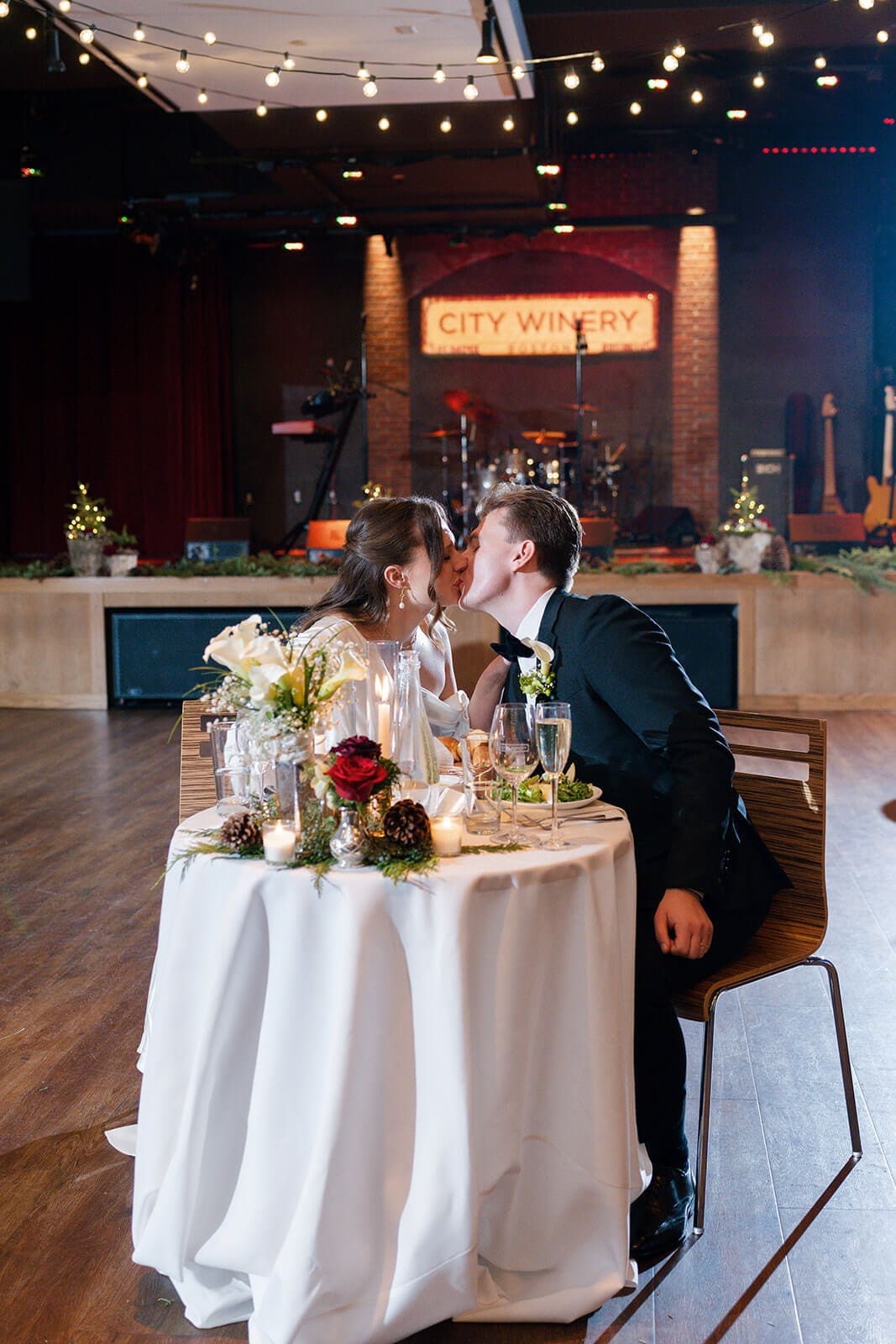 Candid wedding photos of the newlyweds kissing at their candlelit sweetheart table.