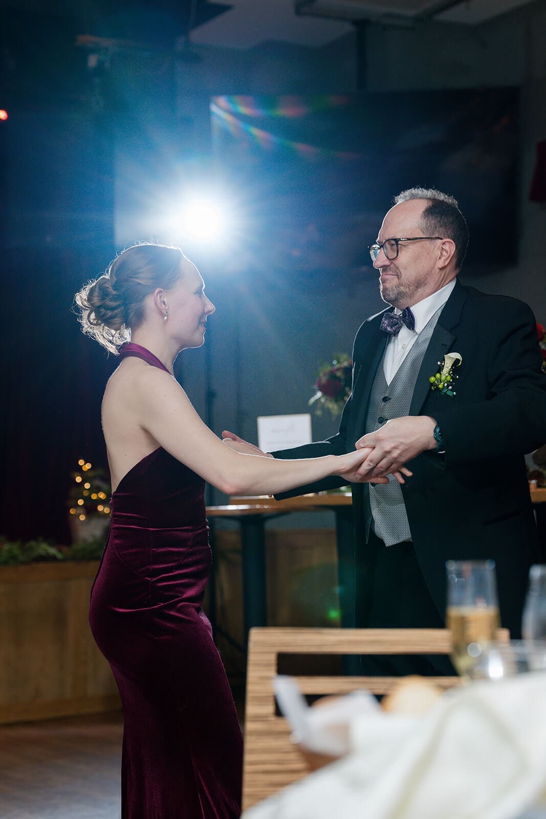 Candid wedding photos of two guests holding hands while dancing together during the reception.