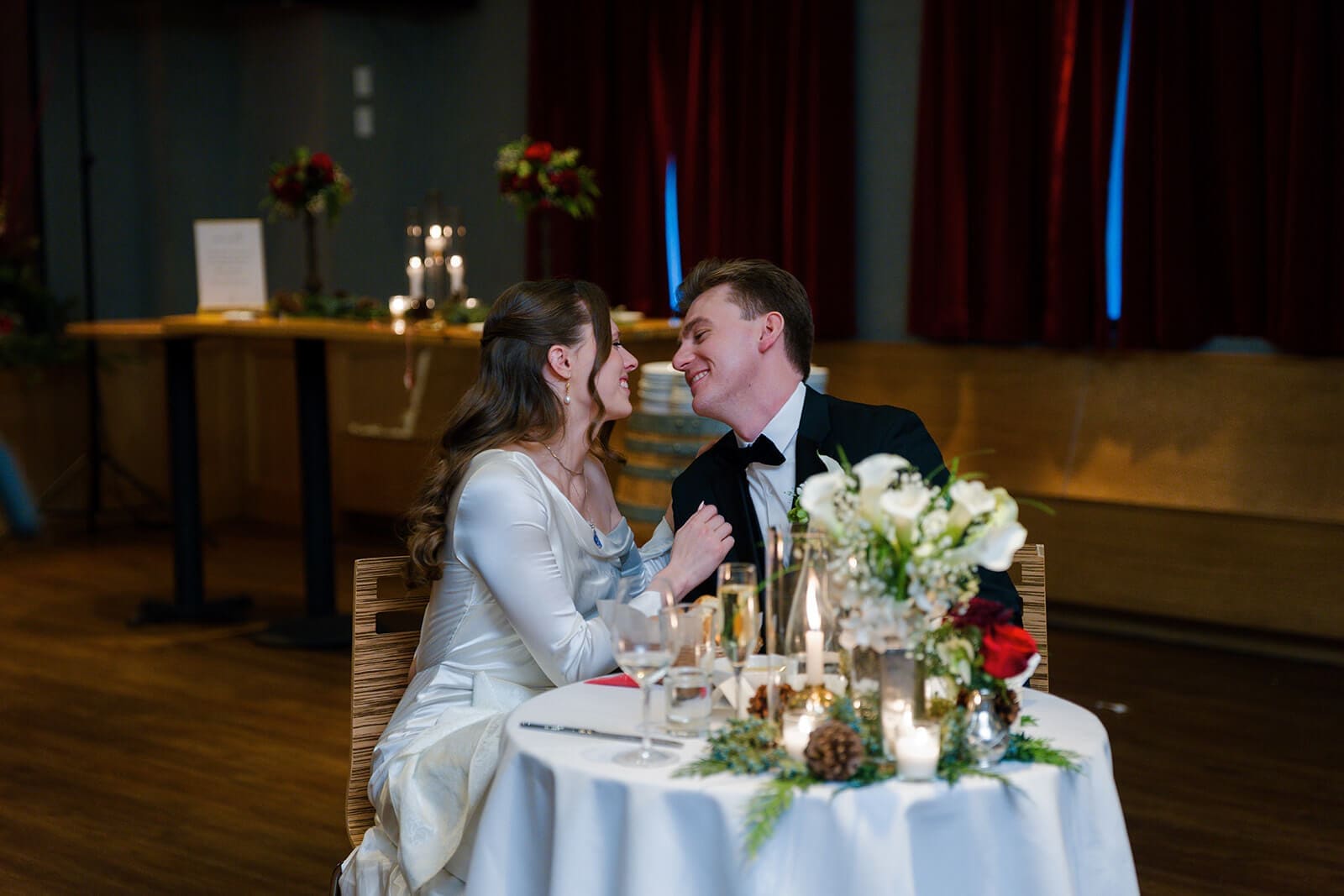 Candid wedding photos of the newlyweds leaning close and smiling at their sweetheart table.