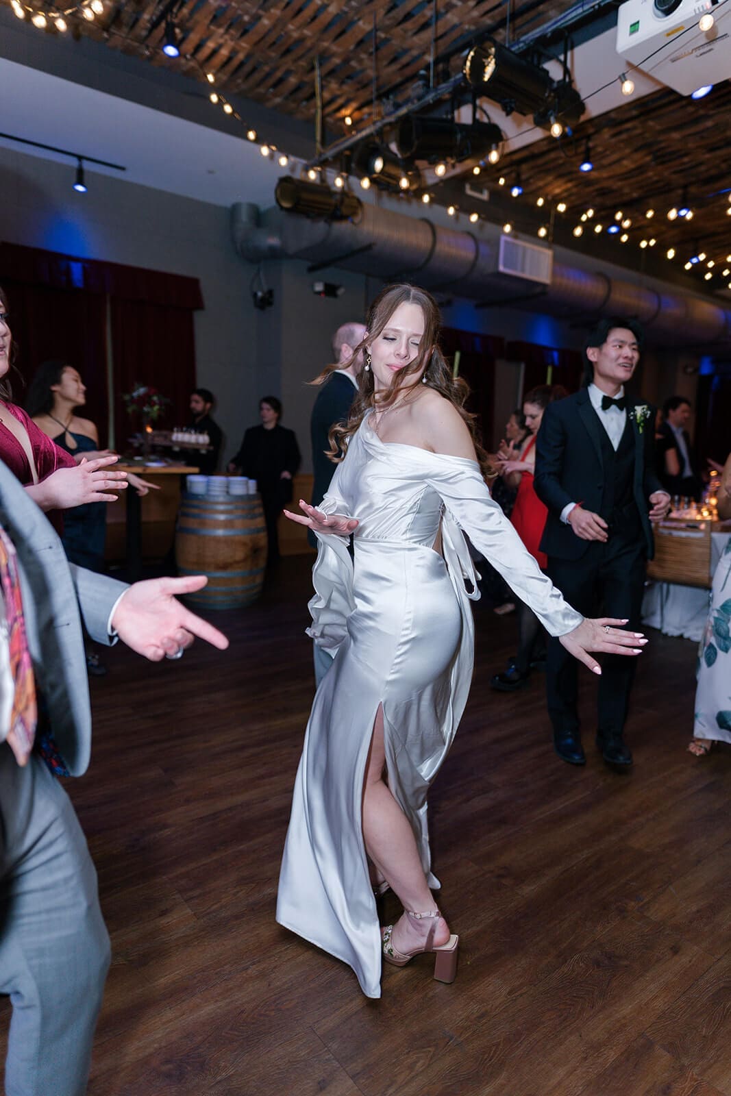Candid wedding photos of the bride dancing freely while the groom and guests celebrate behind her.