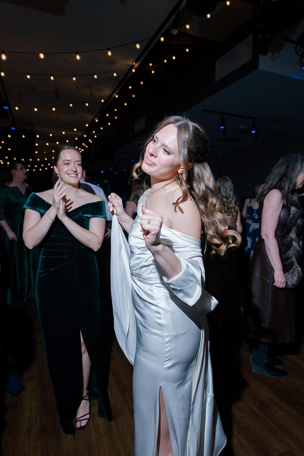 Candid wedding photos of the bride dancing with a guest in a green velvet dress.