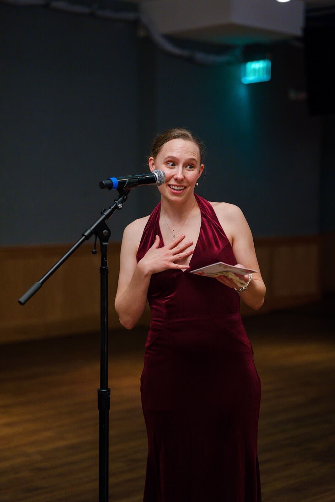 Candid wedding photos of a bridesmaid in a burgundy dress giving an emotional reception speech.