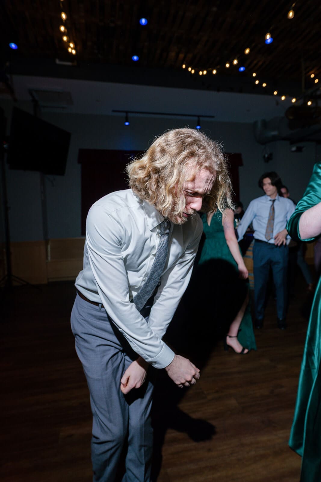 Candid wedding photos of a guest leaning into his dance moves during the wedding reception.