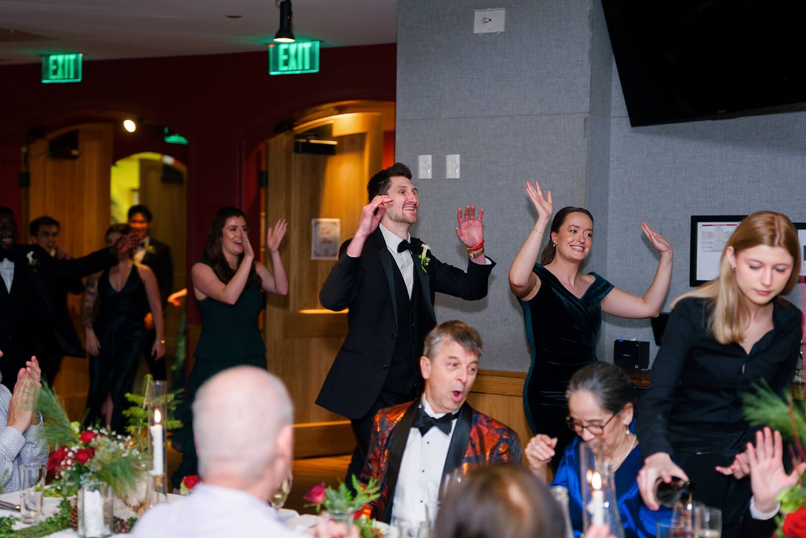 Candid wedding photos of wedding party members entering the reception with their hands raised.