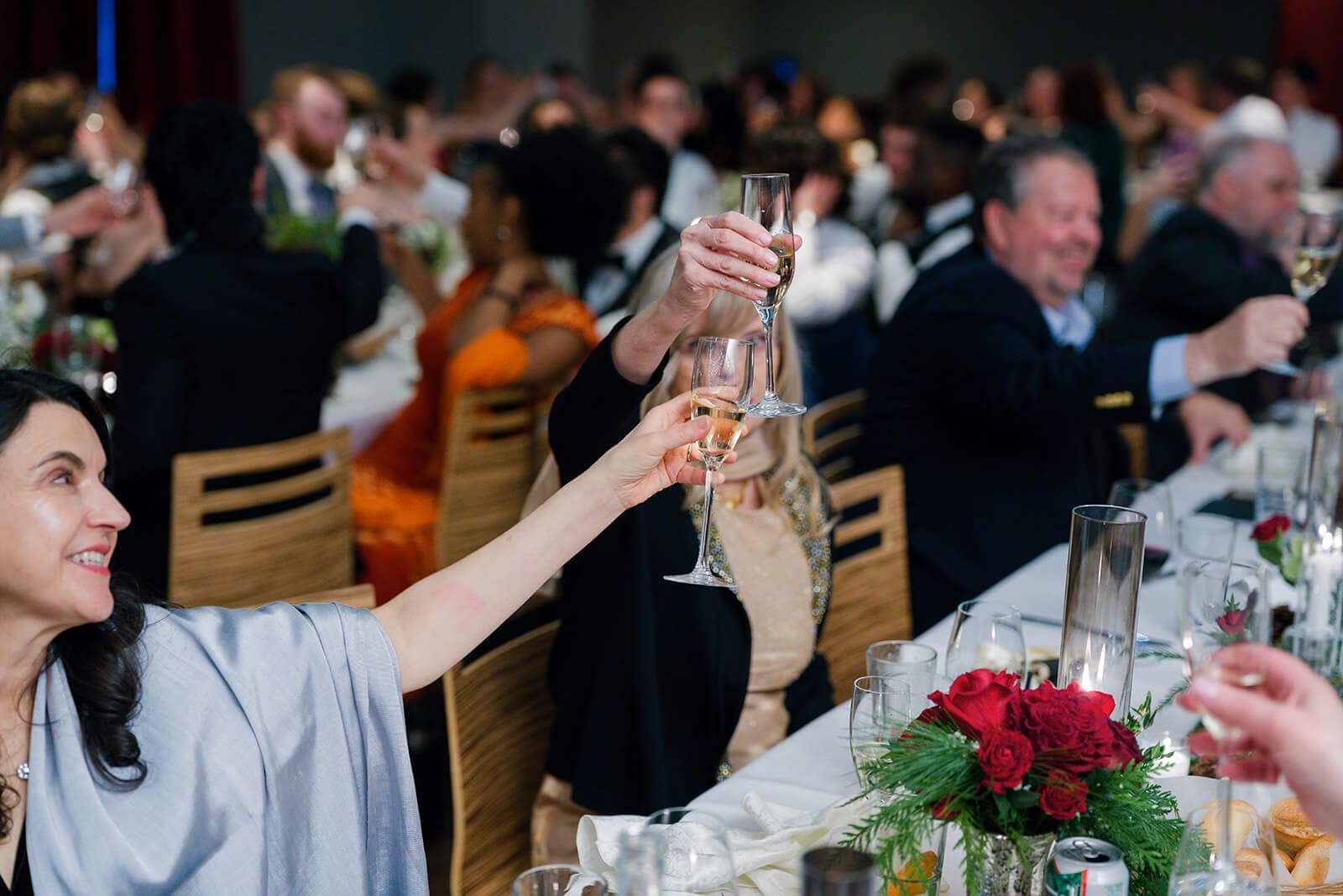 Candid wedding photos of wedding guests raising champagne glasses during a reception toast.