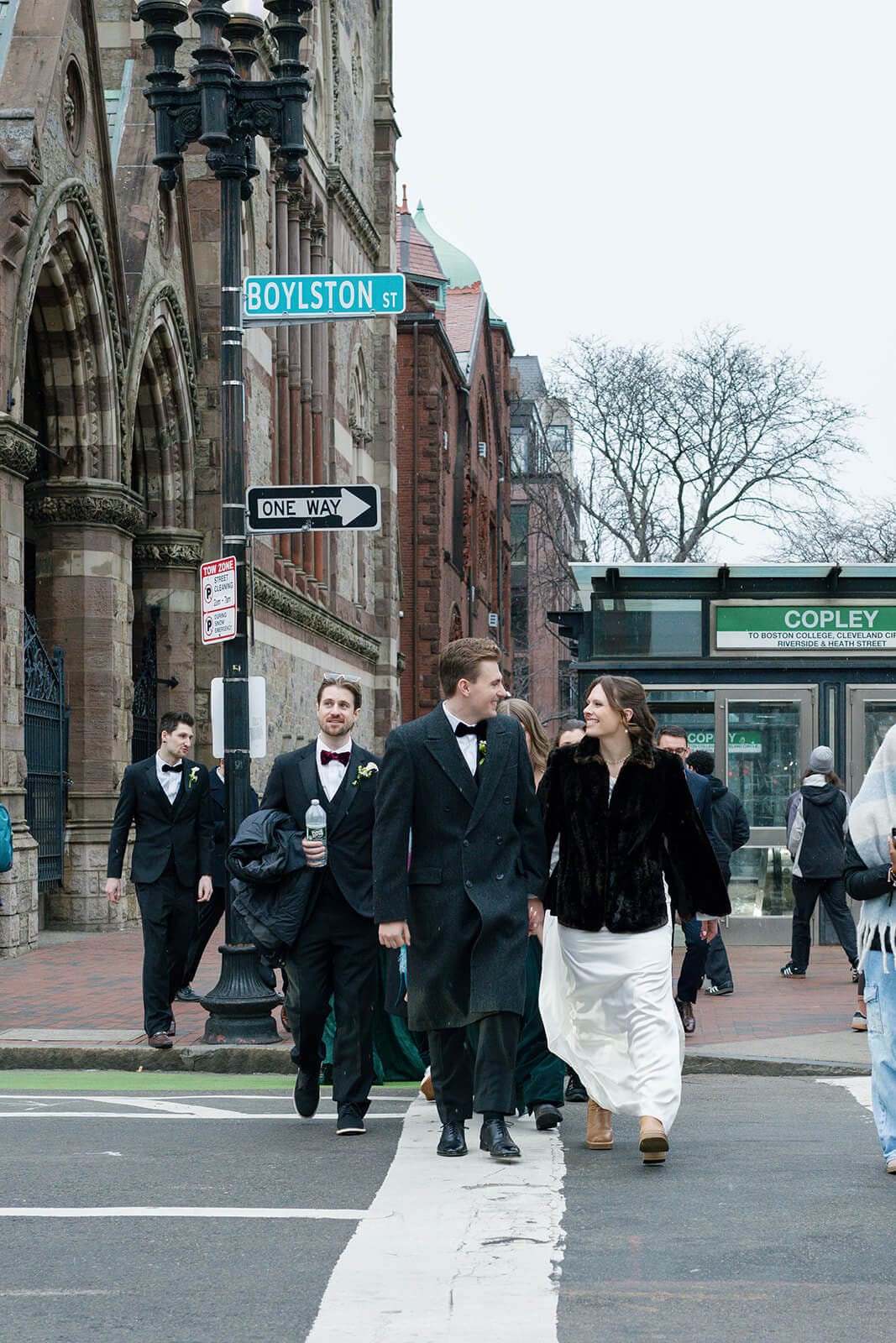 Bride and groom crossing Boylston Street with their wedding party in downtown Boston.