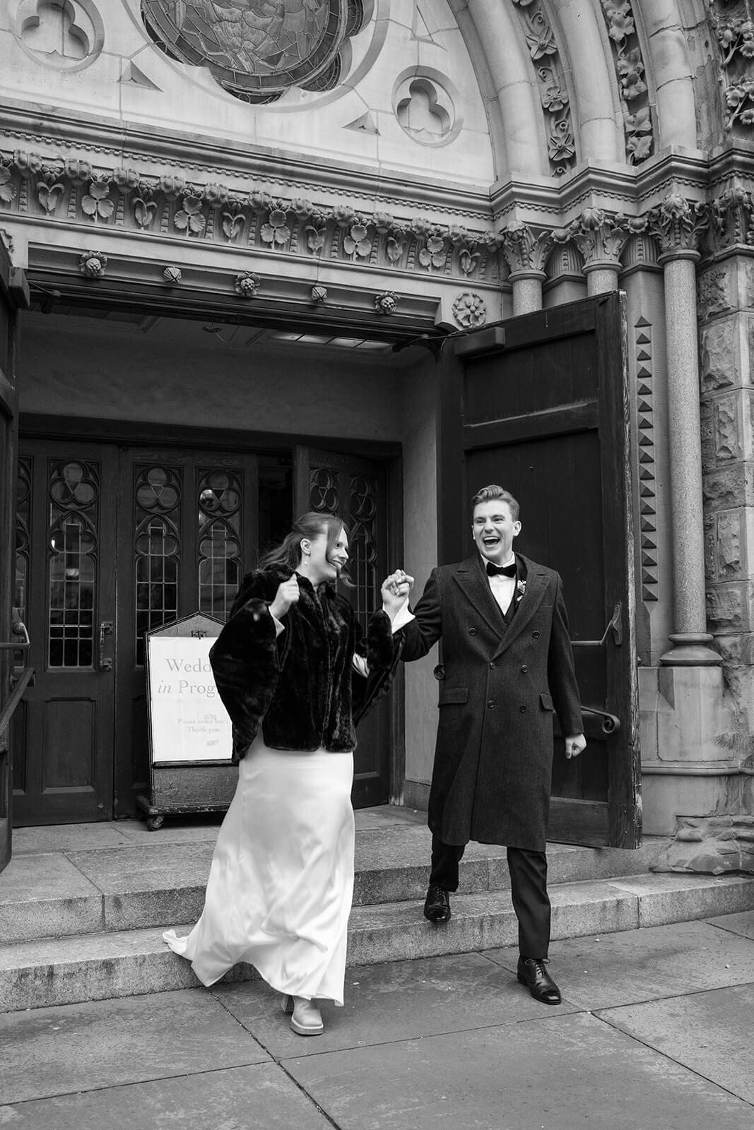 Black and white photograph of newlyweds laughing together outside their historic Boston church.