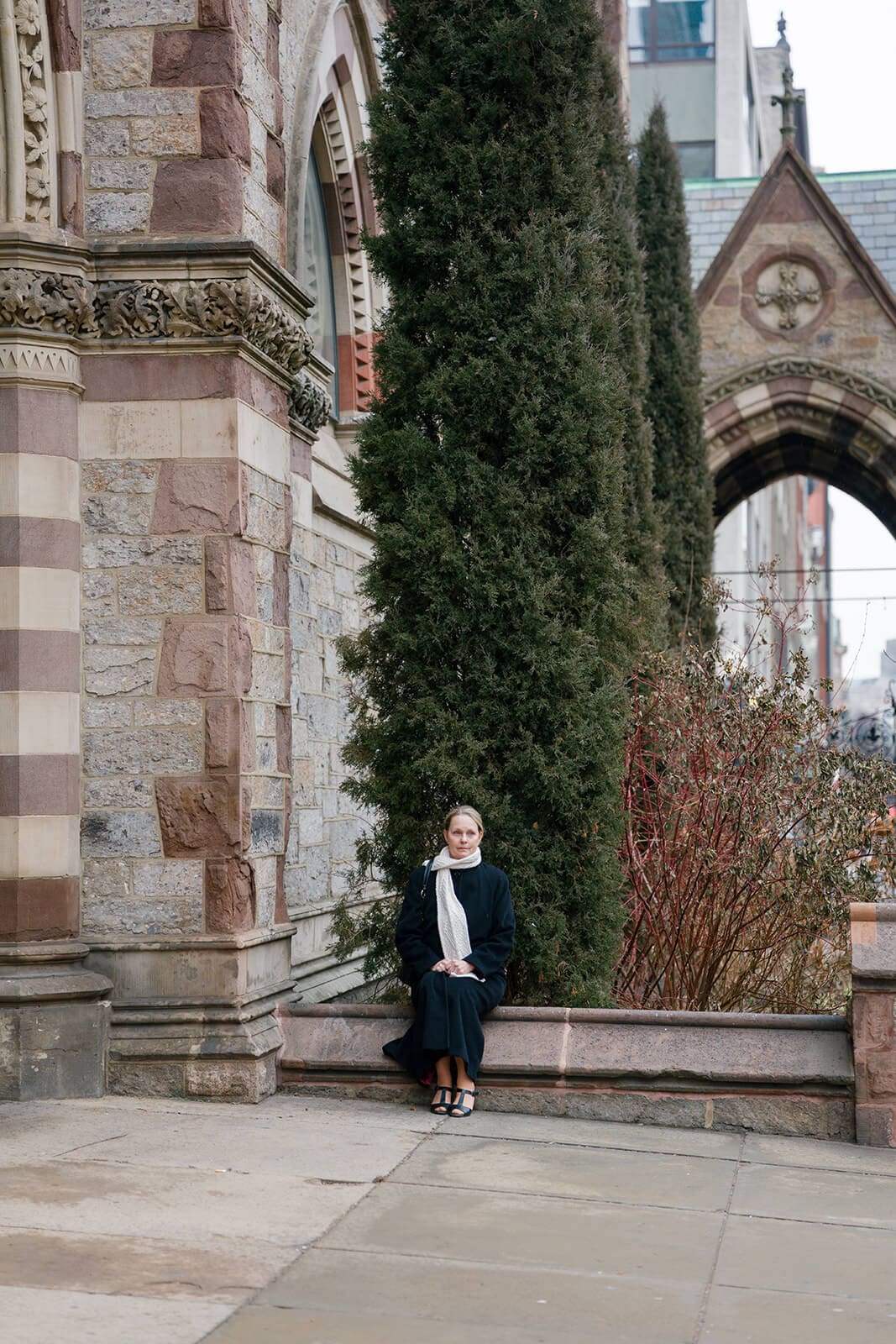 Wedding guest sitting outside a historic church in Boston as other guests exit after the ceremony.