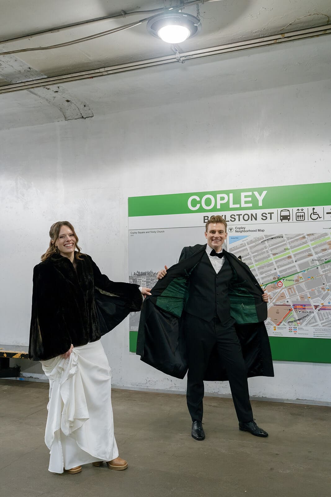Bride and groom laughing and moving together beside the Copley station map in Boston.