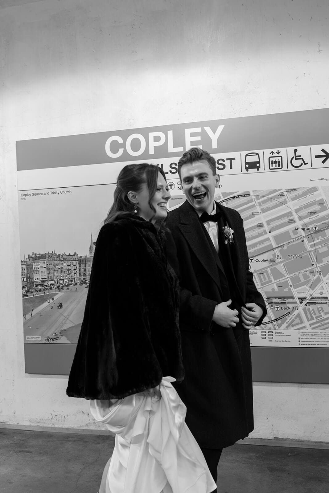 Bride and groom standing beside a transit map inside Copley MBTA station in Boston.