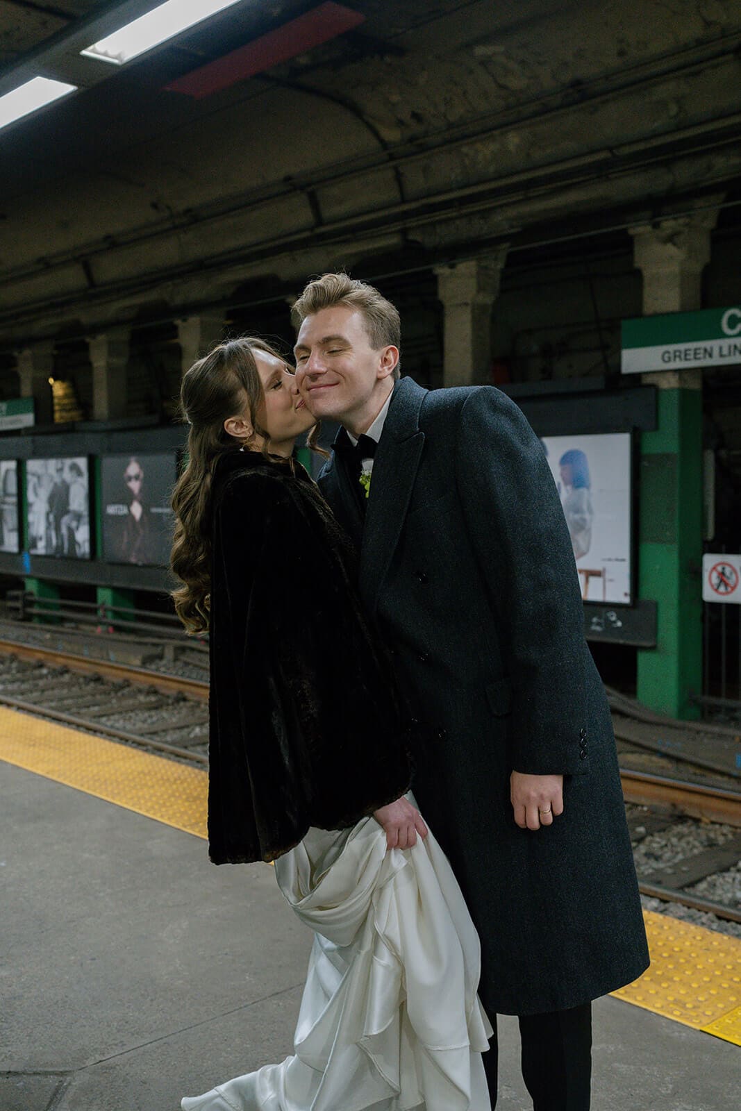Bride and groom sharing a kiss on the Green Line platform at Copley station in Boston.