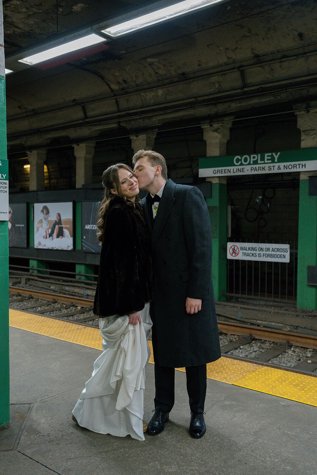 Bride and groom sharing a kiss while waiting on the Green Line platform at Copley station.