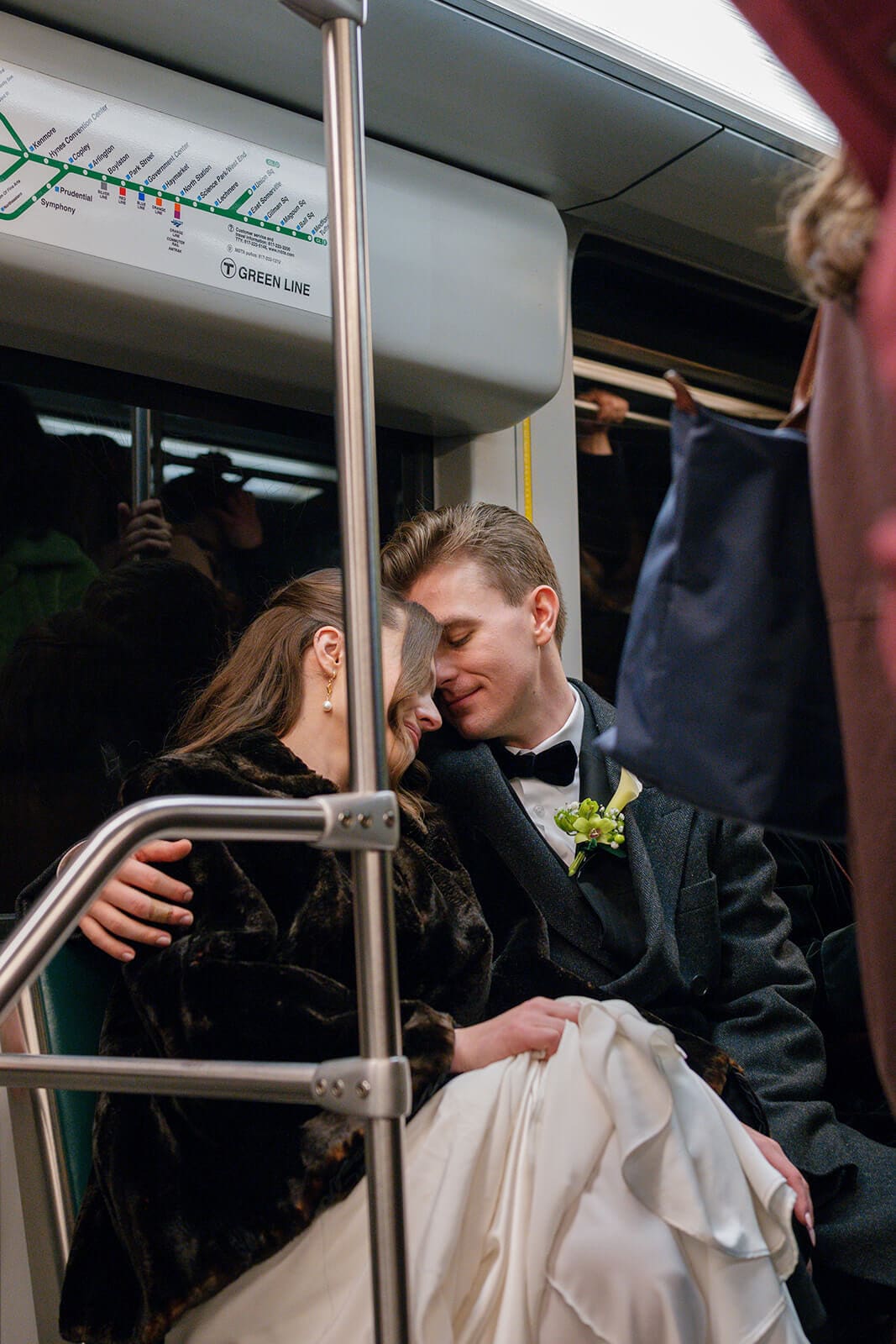 Bride and groom sharing a quiet kiss inside a Boston MBTA train after their wedding ceremony.
