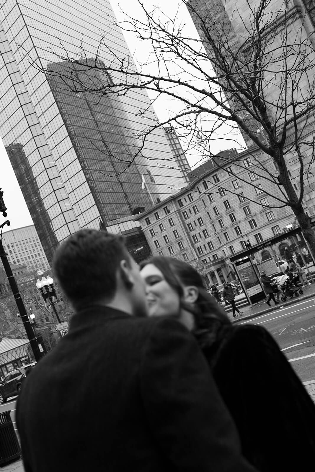 Black and white candid wedding photograph of a couple framed by downtown Boston architecture.