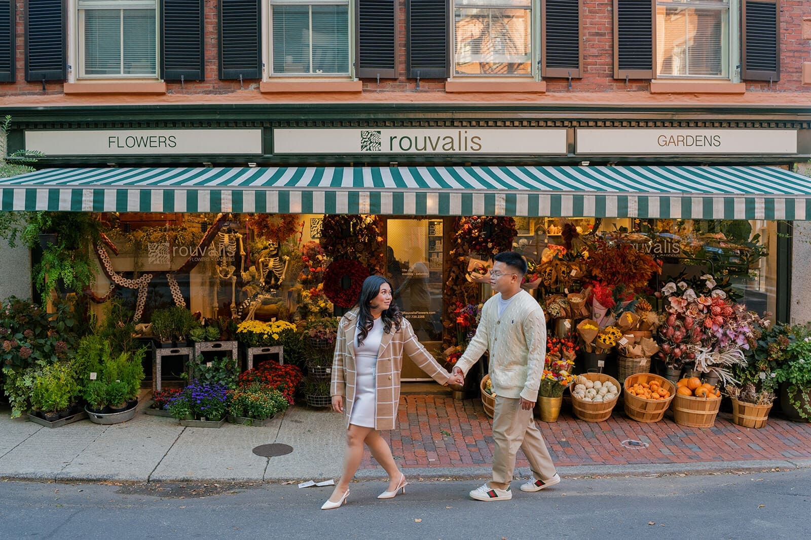 Couple walking hand in hand past the colorful flower displays outside Rouvalis Flowers on Beacon Hill.