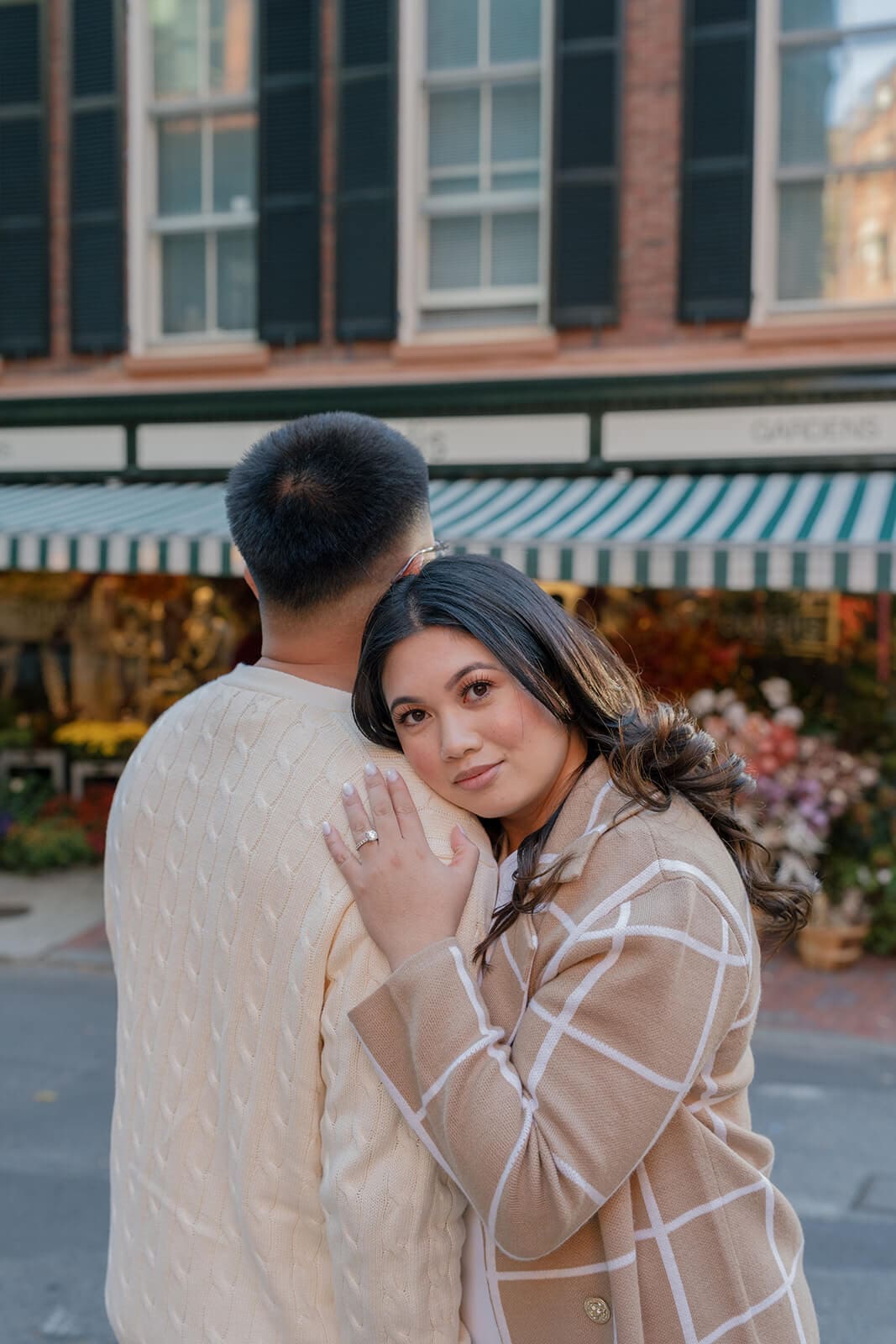 Close portrait of a woman resting against her partner’s shoulder in front of a flower shop on Beacon Hill.