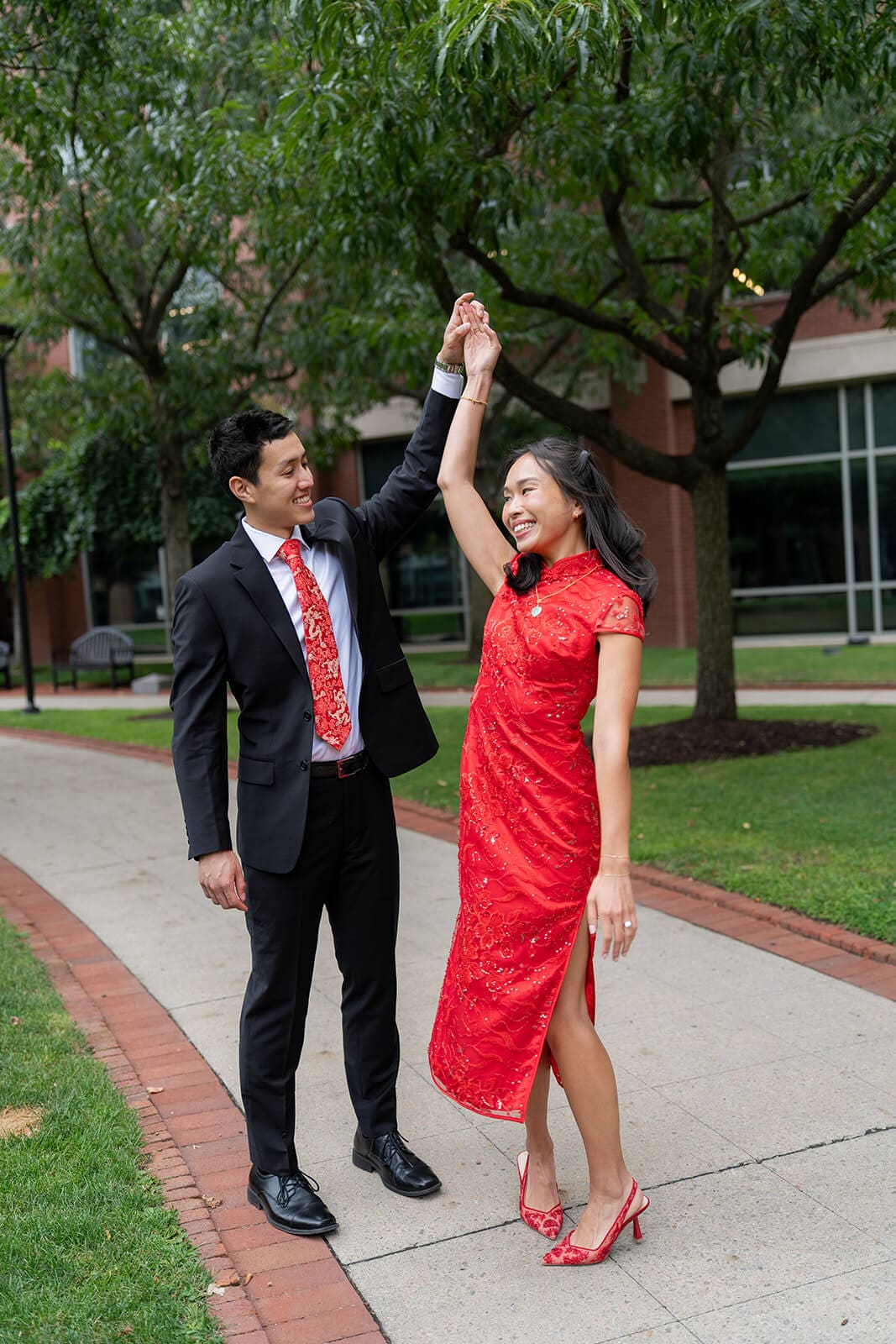 Couple smiling as the man twirls his partner in her red embroidered dress during their pagu restaurant wedding celebration.