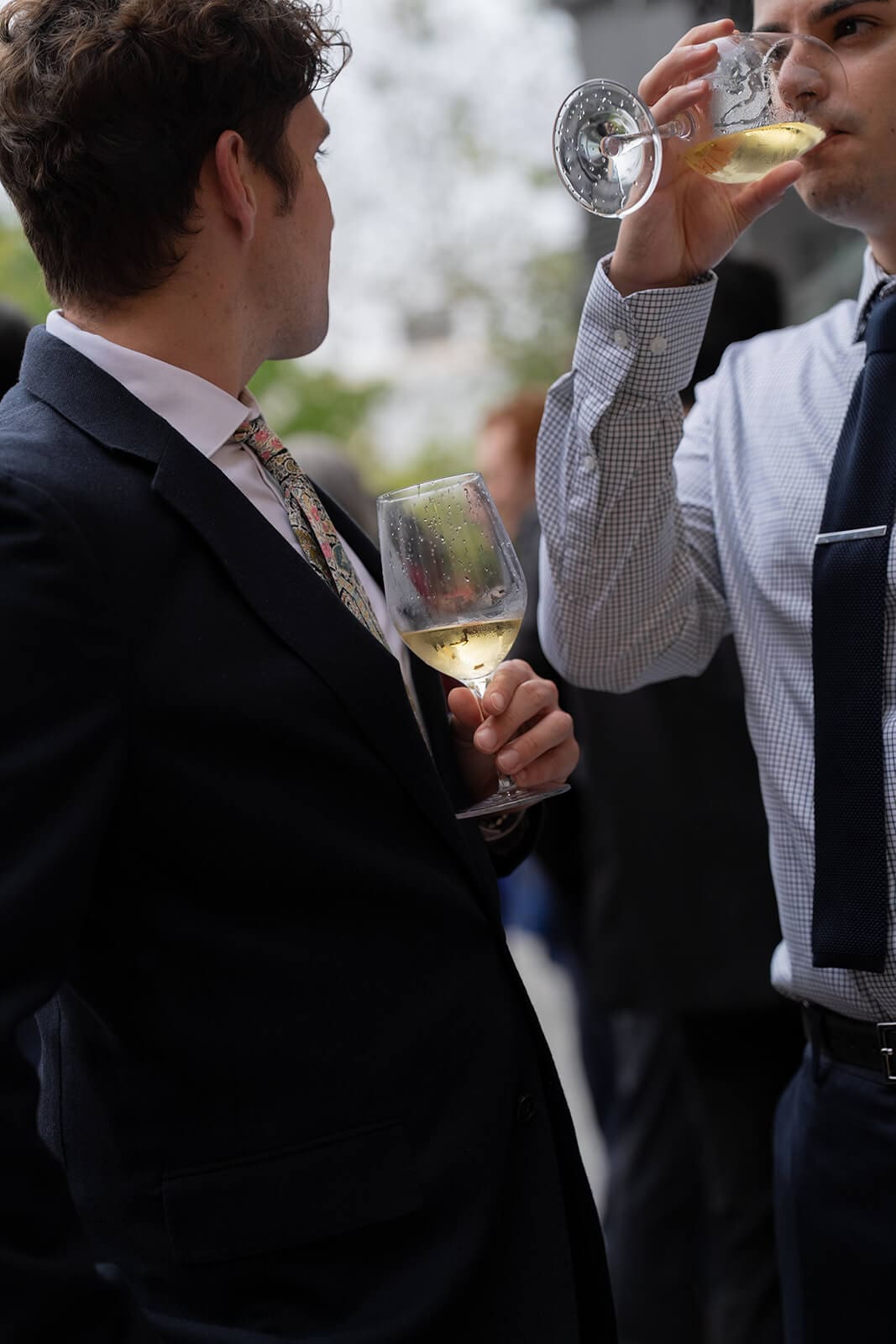 Wedding guests holding glasses of white wine while mingling during a pagu restaurant wedding reception.