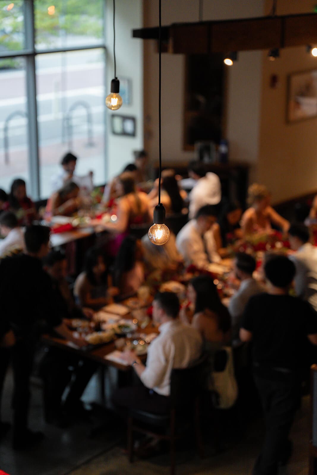 Elevated view of guests seated around a long dining table during a pagu restaurant wedding reception dinner.