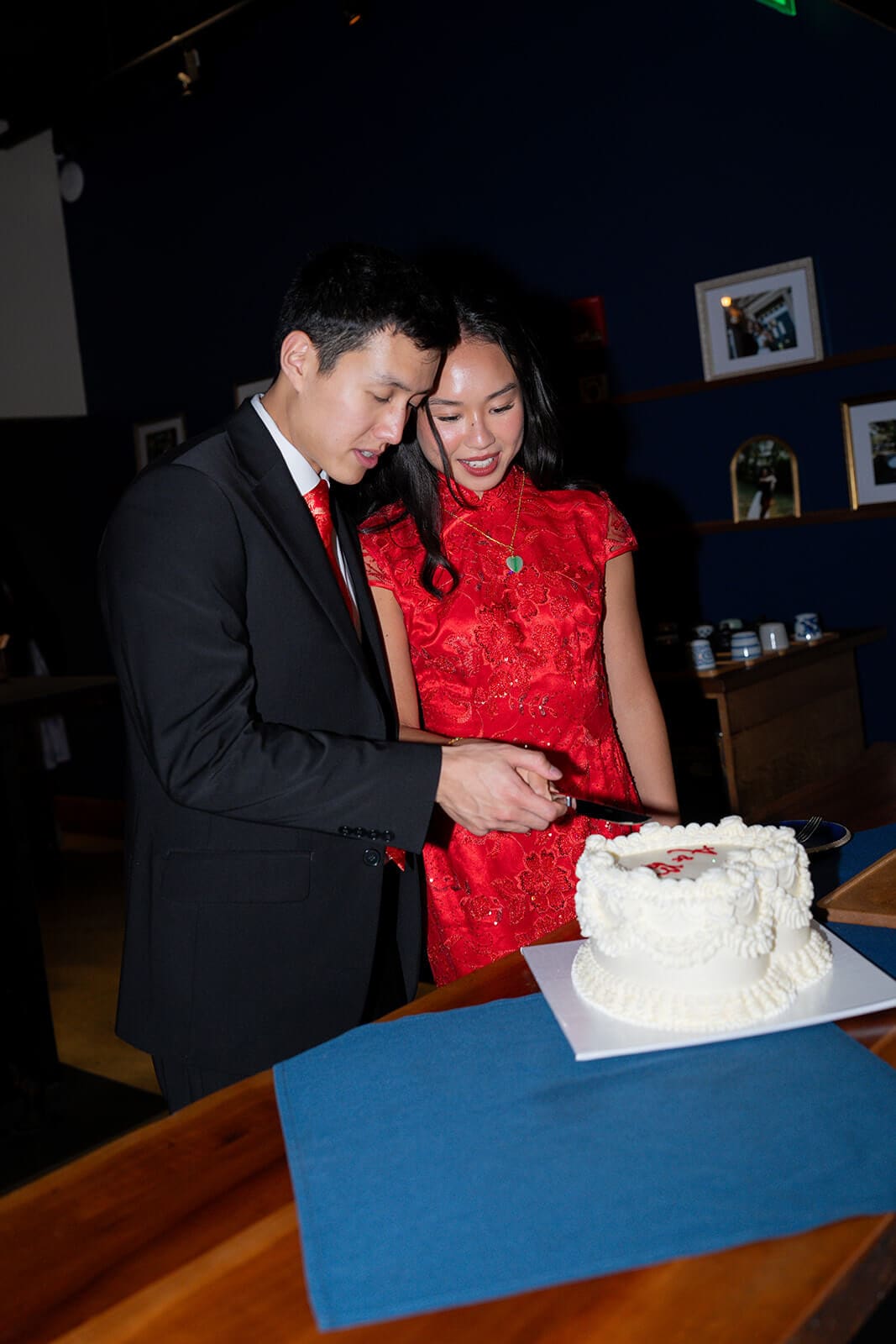 Couple cutting their white heart-shaped cake together inside the restaurant.