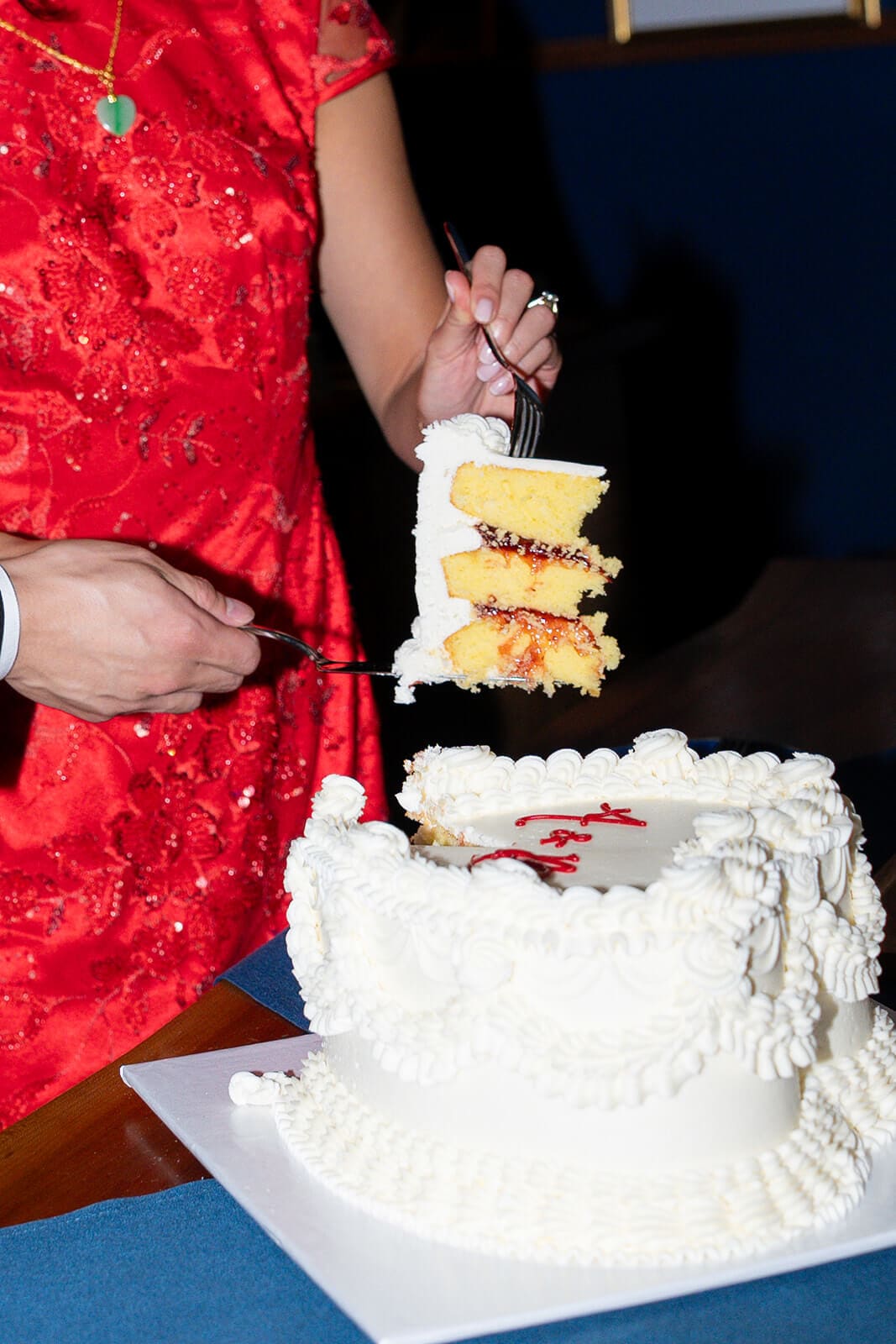 Couple serving a large slice from their white heart-shaped wedding cake.