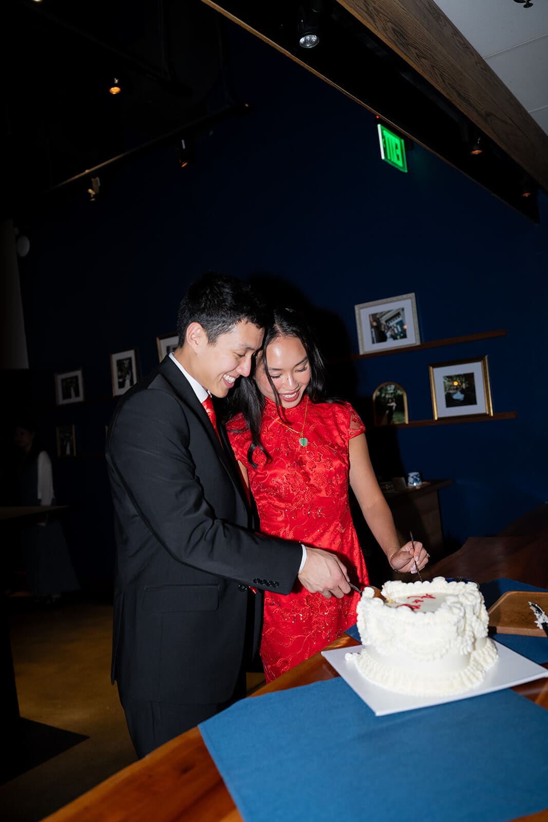 Couple smiling while cutting their cake together during their pagu restaurant wedding reception.