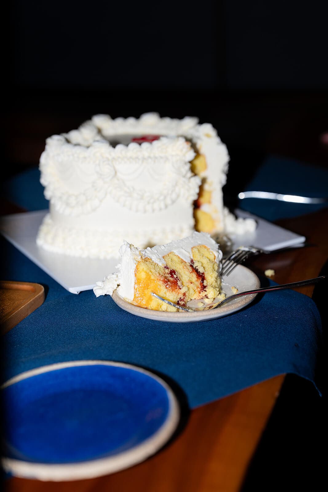Partially sliced white heart-shaped cake revealing yellow cake and red fruit filling at a pagu restaurant wedding.