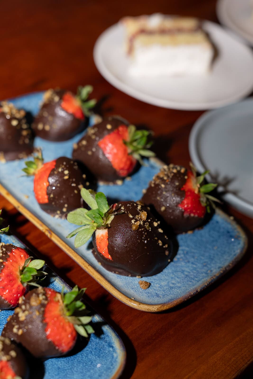 Chocolate-covered strawberries arranged on blue serving plates.