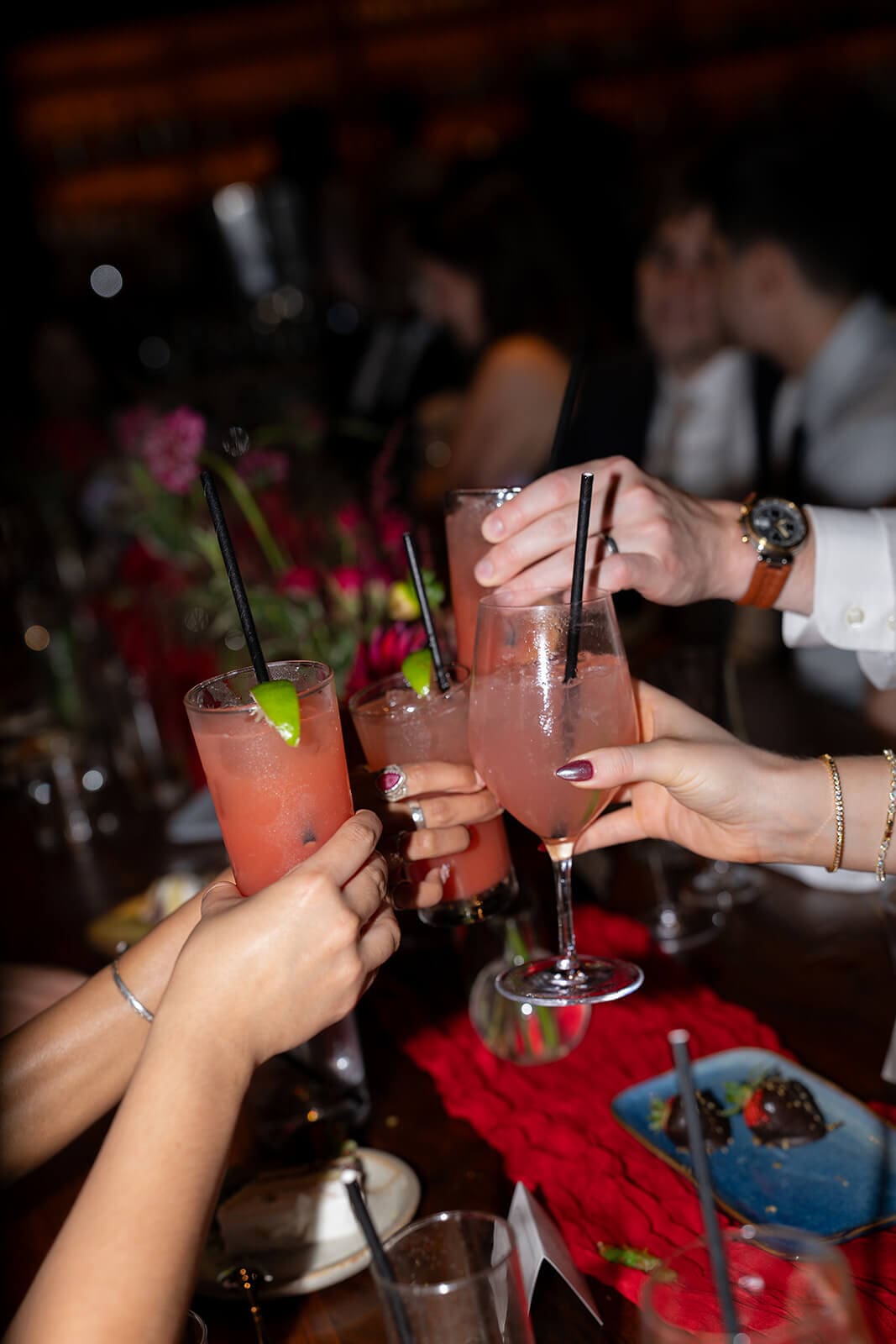 Guests raising pink cocktails together in a celebratory toast.