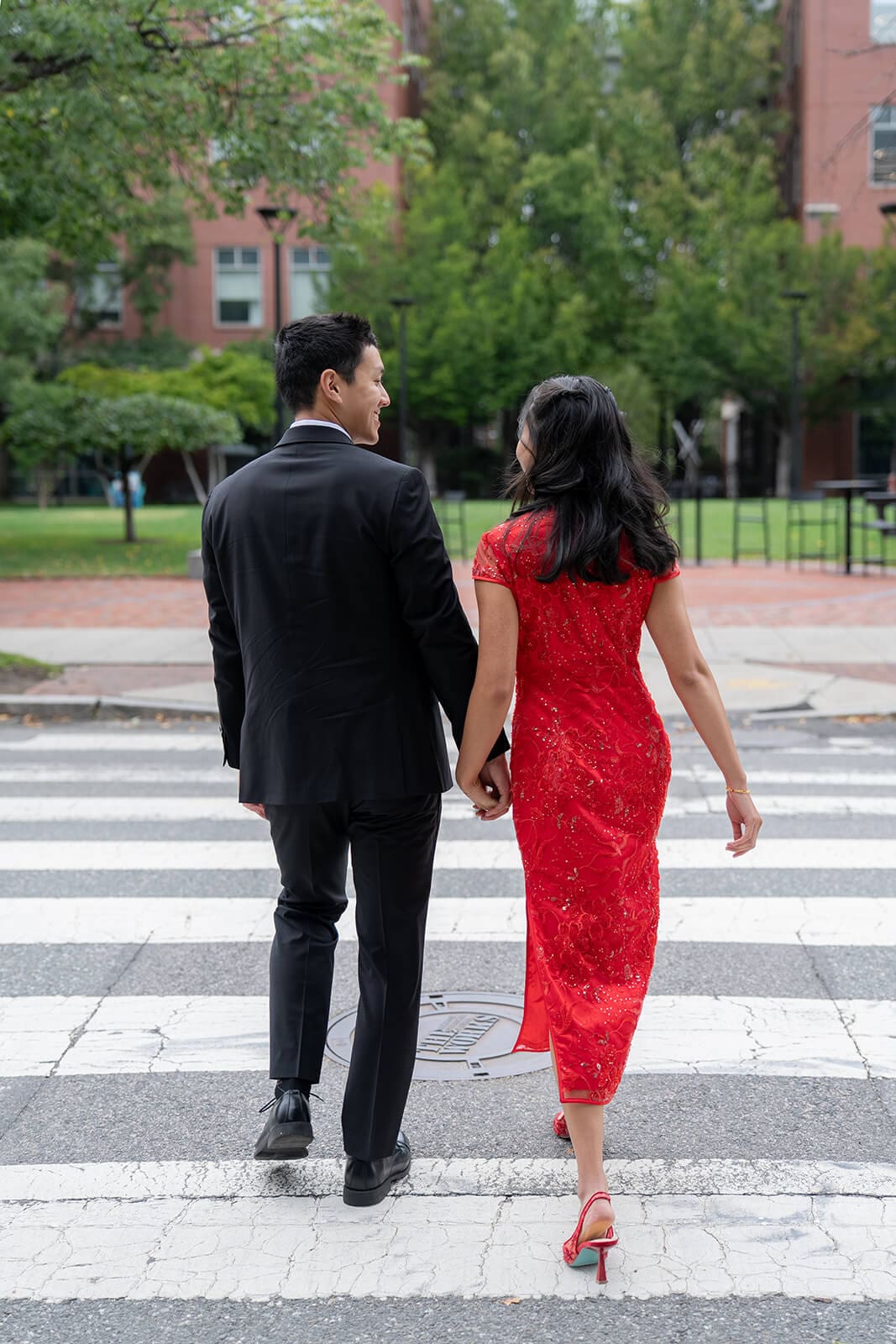 Couple walking hand in hand across a city crosswalk after their pagu restaurant wedding celebration.