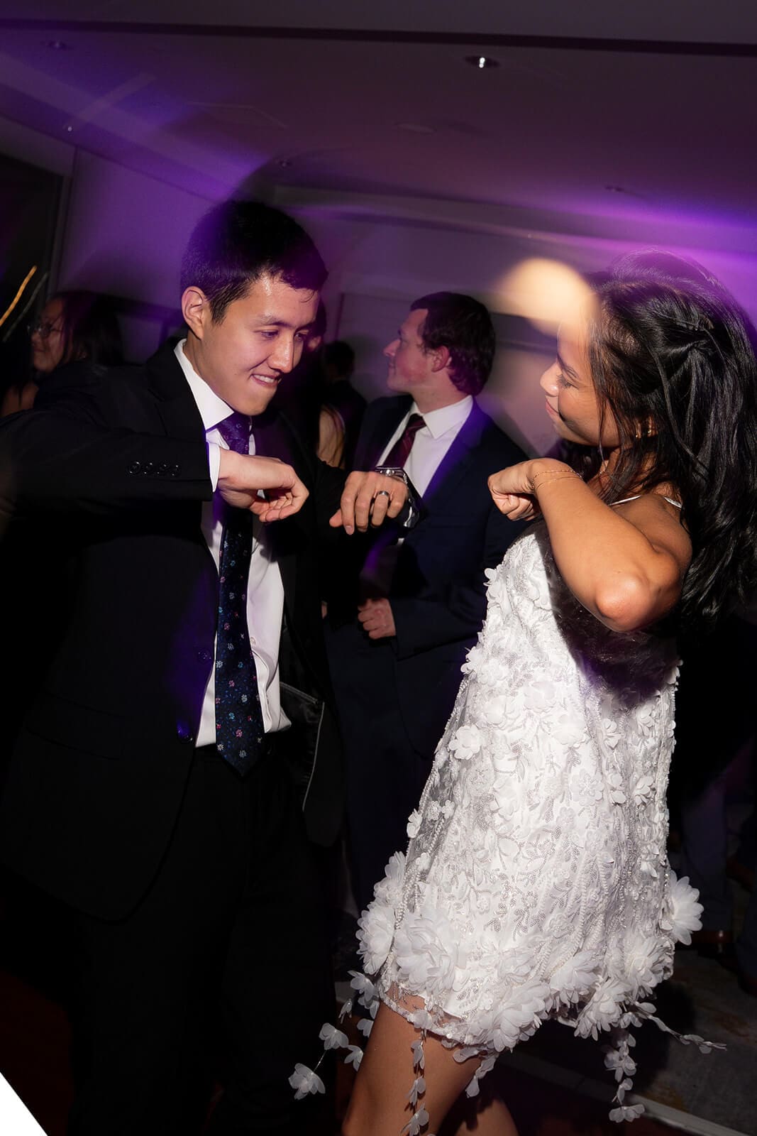 Couple dancing together beneath purple reception lighting during their pagu restaurant wedding celebration.