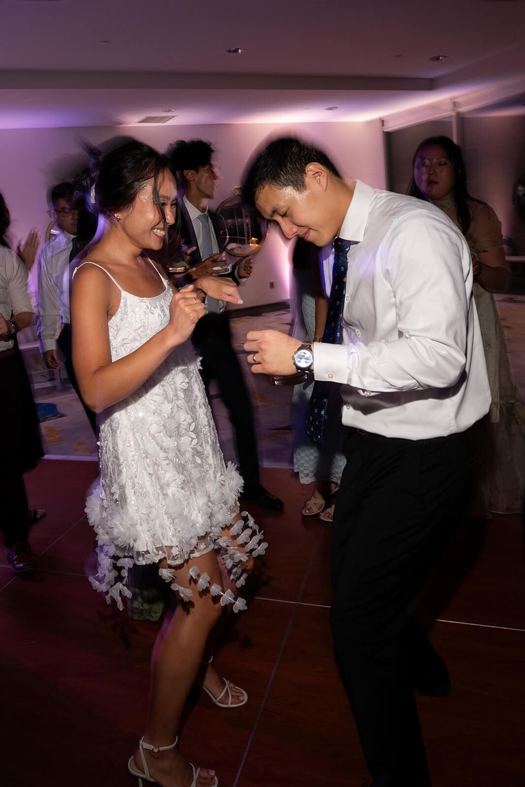 Couple laughing and dancing together on the reception dance floor.