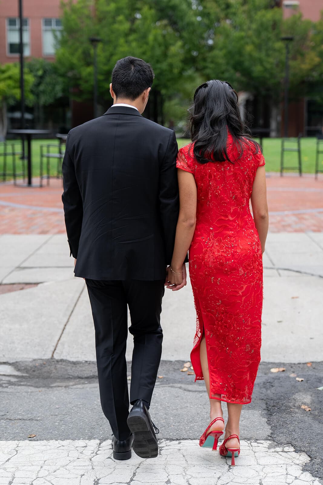 Couple holding hands while walking away together through a city courtyard during their pagu restaurant wedding portraits.