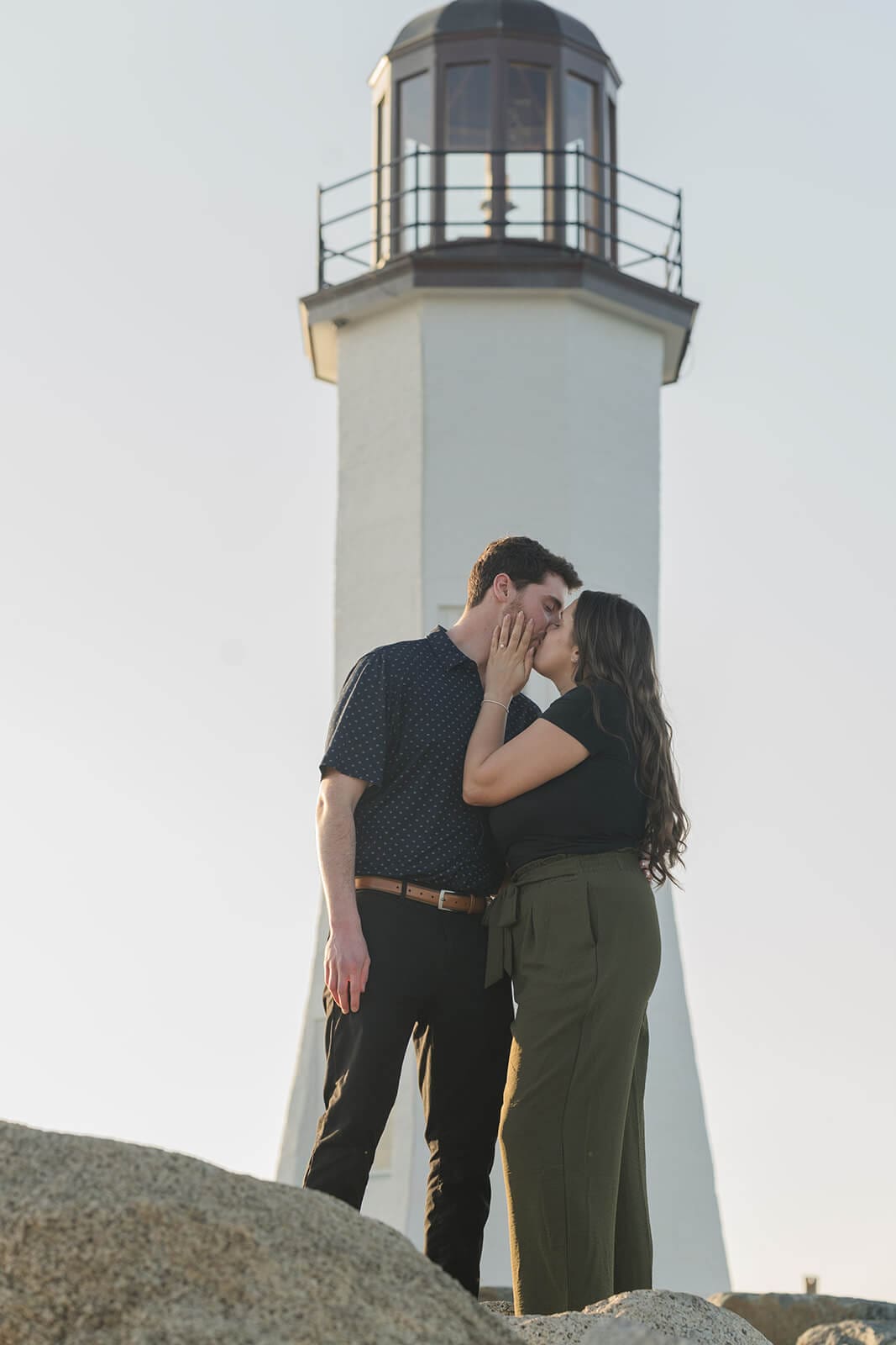 Newly engaged couple kissing in front of Scituate Lighthouse