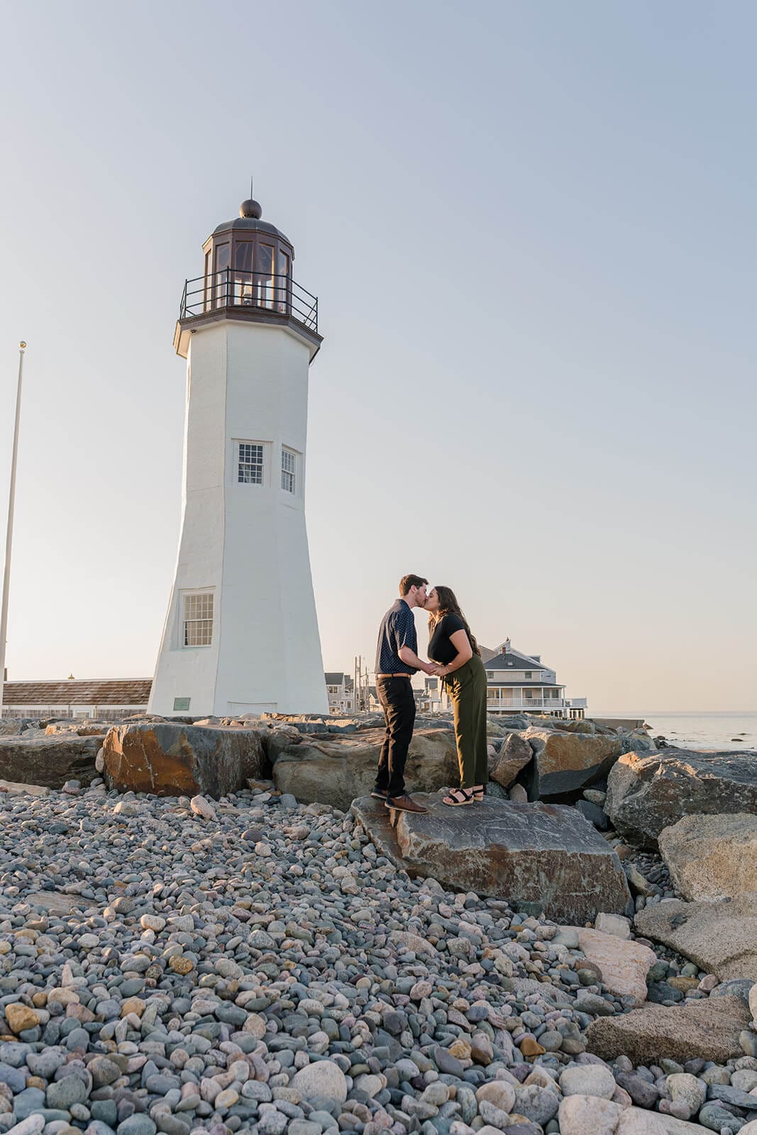 Couple kissing among the rocks with Scituate Lighthouse behind them