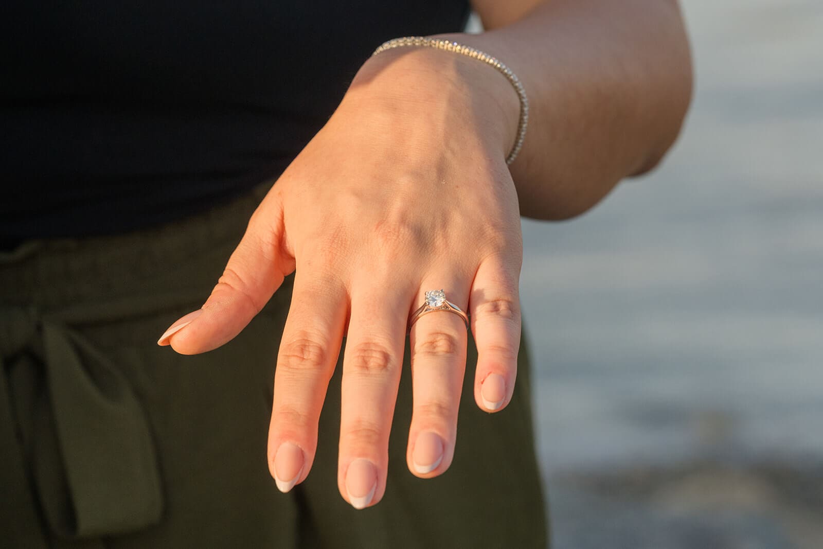 Close-up of a woman’s hand showing her diamond engagement ring and bracelet