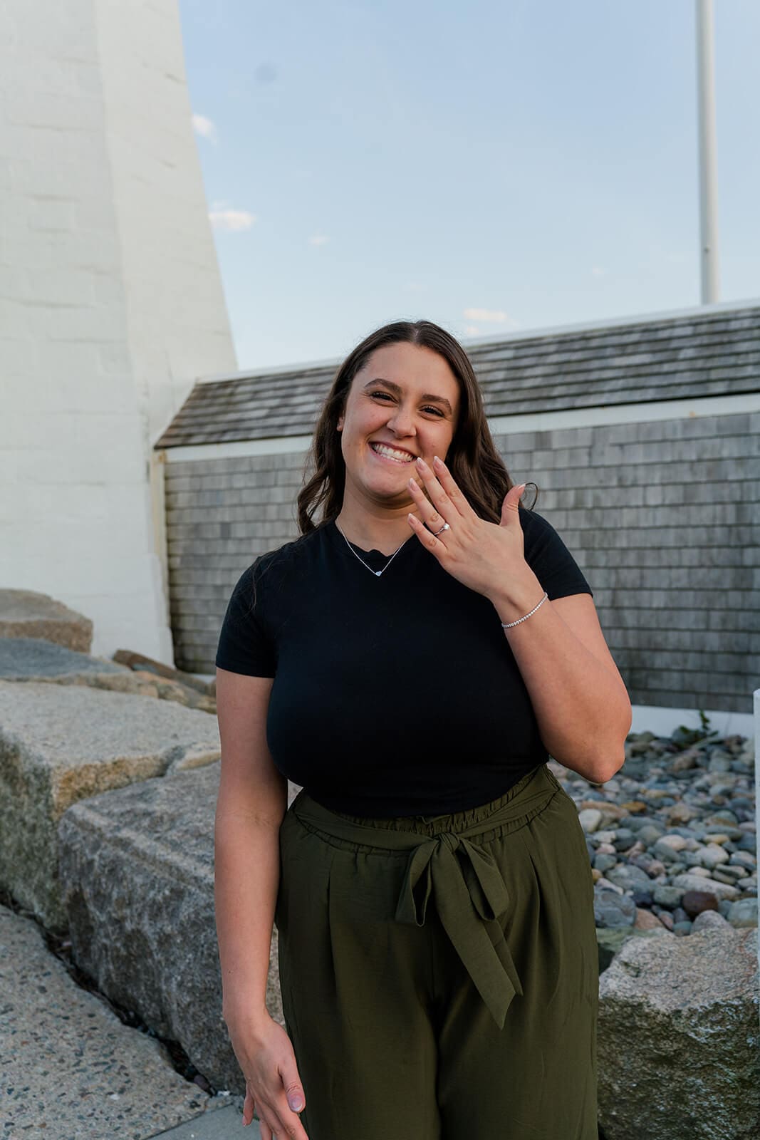 Woman smiling and holding up her engagement ring