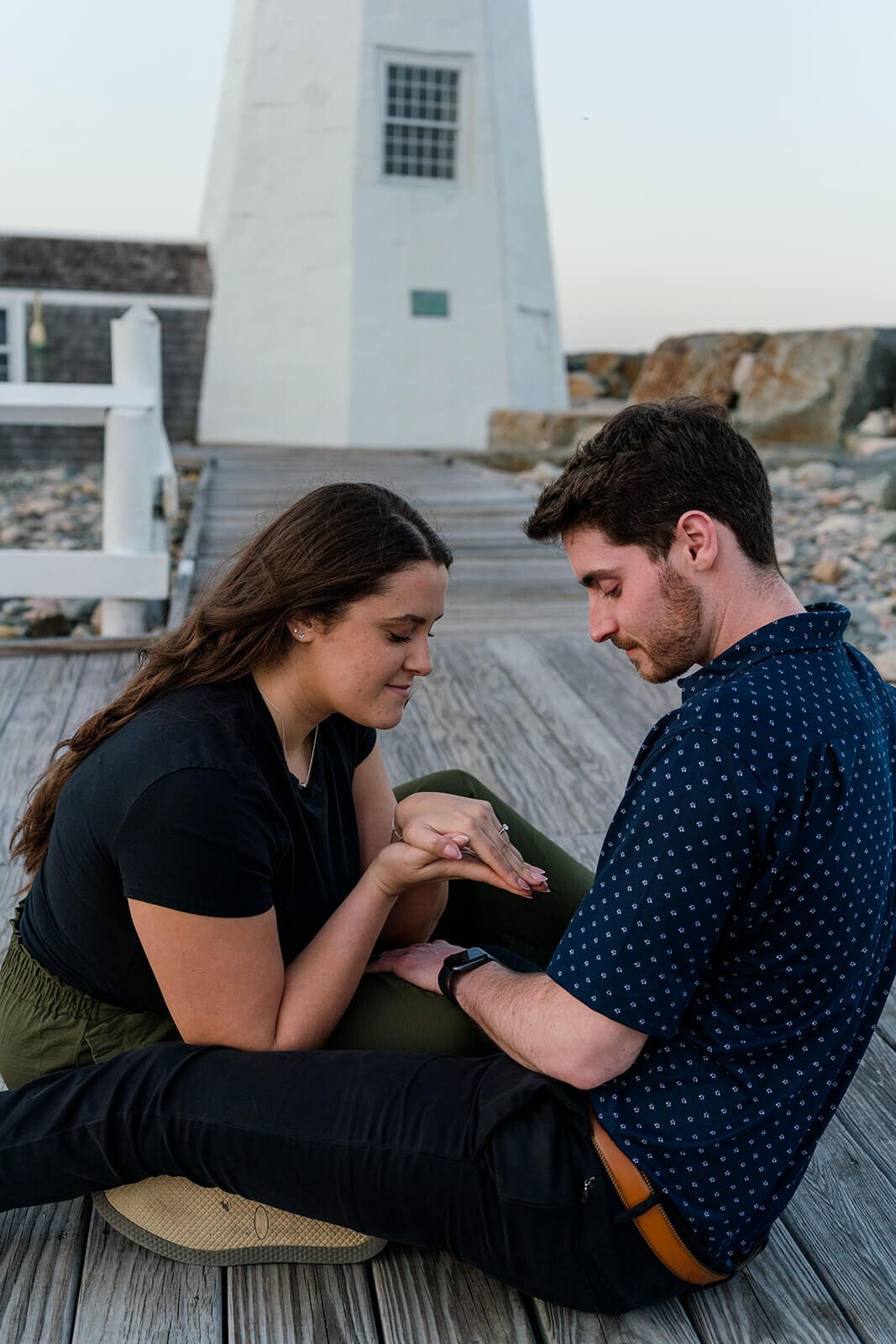 Newly engaged couple looking down at her engagement ring while sitting together