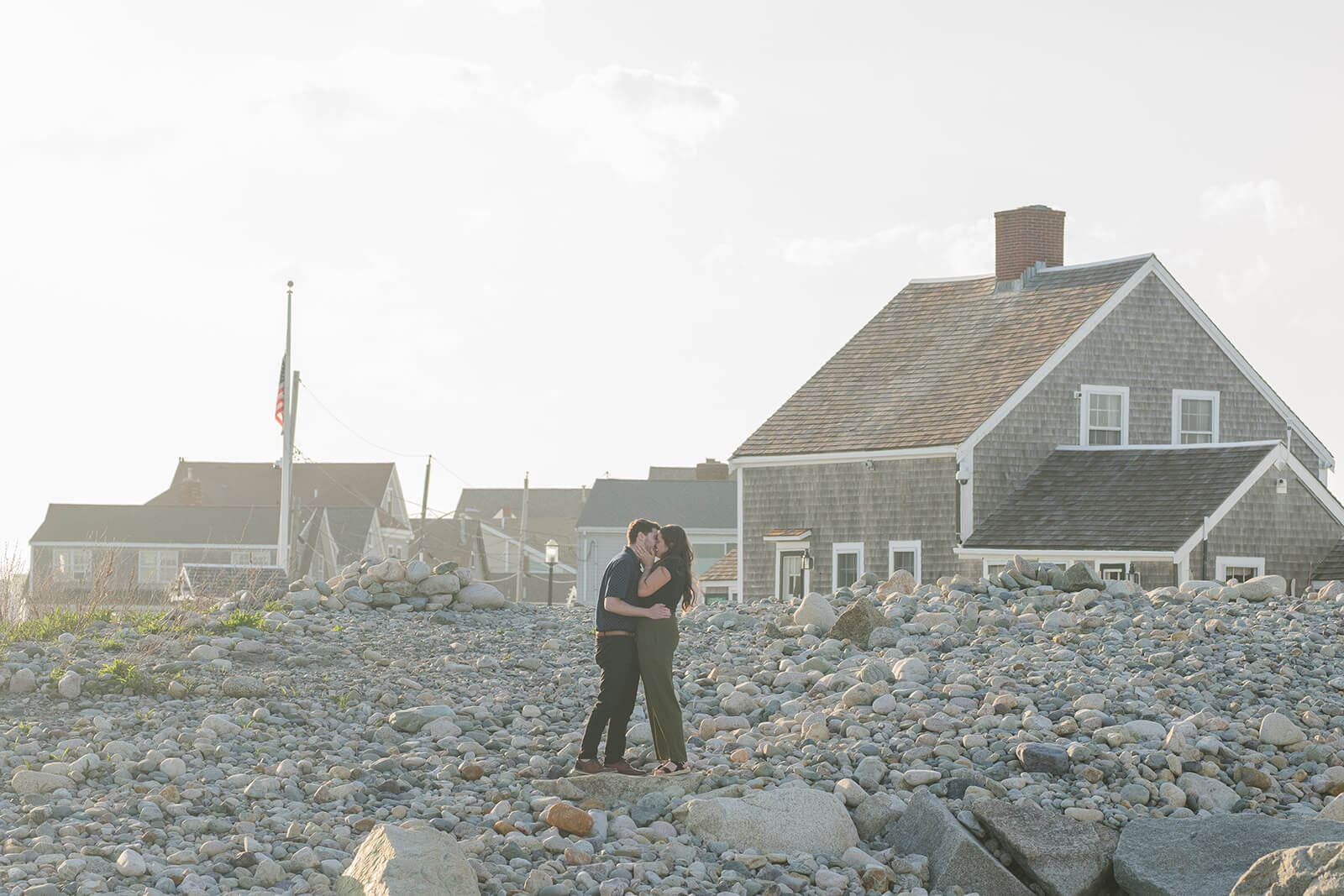 Newly engaged couple embracing on the rocks near Scituate Lighthouse